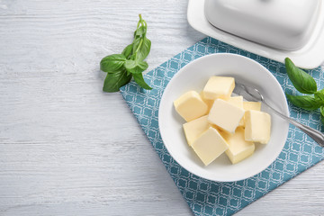 Wall Mural - Bowl with cubes of butter and greens on light table