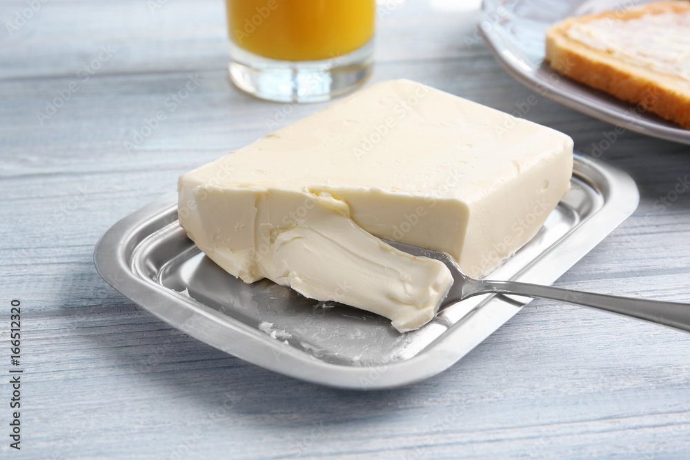 Piece of butter in dish on wooden table