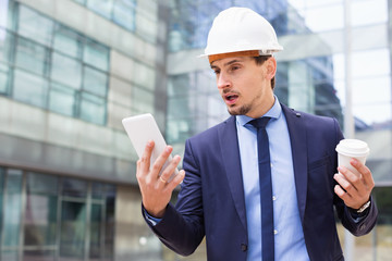 Man in helmet with touchpad and coffee in the hand