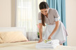© Africa Studio - Young maid putting flowers on stack of towels in hotel room