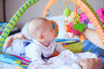 cute little asian 5 - 6 months old baby boy child at tummy time on the play gym playing with his dad