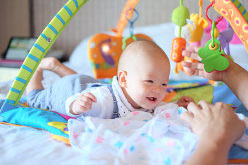 cute little asian 5 - 6 months old baby boy child at tummy time on the play gym playing with his dad