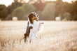 Hund Australian Shepherd sitzt im Feld und hebt das Bein hoch und winkt