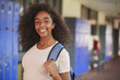 © Monkey Business - Happy black teenage girl smiling in high school corridor