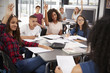 © Monkey Business - High school kids raise hands, teacher sitting at their desk