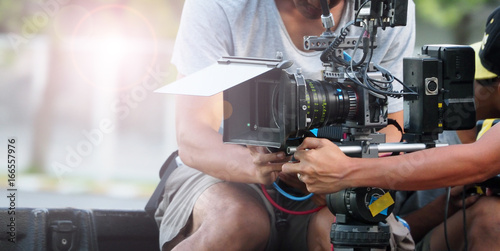 Fotomural Behind the scenes of movie shooting or video production at outdoor location with high quality camera gimbal tripod equipment set up and professional film crew team on sunny day with flare lighting