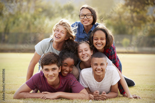 Fotografía Group of teenage friends lying in a pile on grass