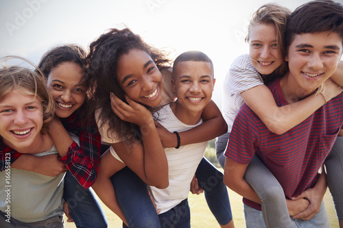 Cuadros en Lienzo Teenage school friends having fun piggybacking outdoors