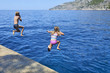 © Petr Bonek - Happy child boy and girl jumping into the blue sea