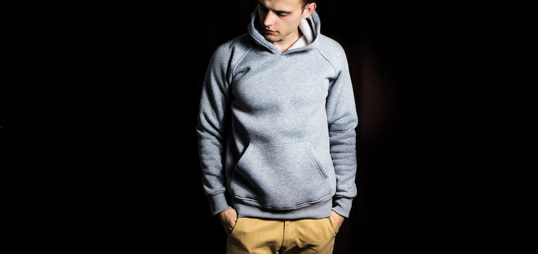 Fototapete - man  in the blank grey hoodie, sweatshirt on a black background, mock up, free space