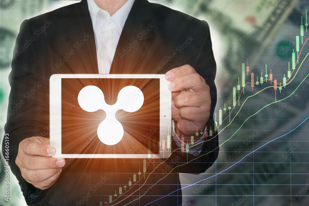 Blockchain concept : Rise of Ripple price. Business man holding tablet showing Ripple symbol on screen with increasing price graph and dollar bills in background.