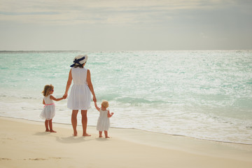 mother with two daughters walk on beach