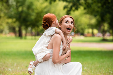 mother piggybacking daughter in park