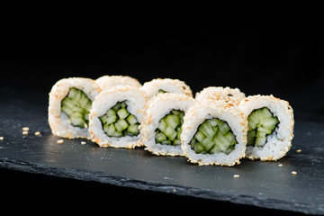 Canvas Print - Traditional Japanese cuisine.  Selective focus on sushi rolls with cucumber, cream cheese, rice, sesame seeds on dark background