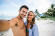 © AlejandroMCB photo & film/Stocksy - Young happy couple taking a self-portrait on the white sand of the caribbean beach