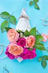 Wall Mural - Fresh pink and orange roses in paper cover over blue background