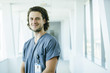 © Inti St. Clair - Portrait of confident, happy male nurse in hospital hallway