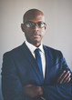 © Flamingo Images - African executive in a suit standing wth his arms crossed