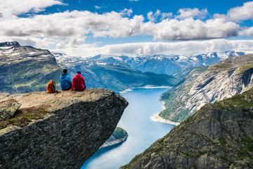 Wall Mural - Couple sitting against amazing nature view on the way to Trolltunga. Location: Scandinavian Mountains, Norway, Stavanger. Artistic picture. Beauty world. The feeling of complete freedom