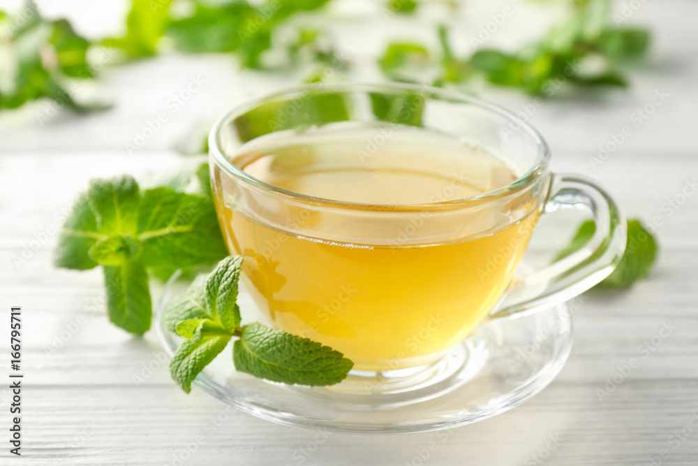Cup of hot aromatic tea with lemon balm on wooden table