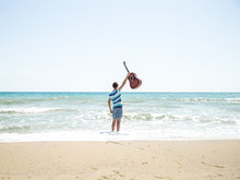 Young Man With Acoustic Guitar On The Beach