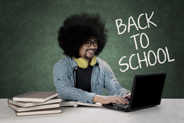 Wall Mural - Afro student typing on a laptop