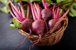 Young beetroot with a tops in a basket on a dark background.