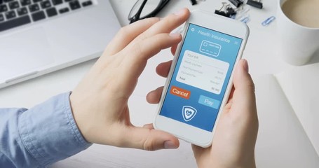 Paying for health insurance using smartphone app sitting at the desk