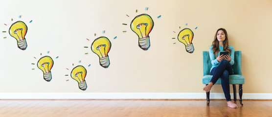 Wall Mural - Light bulbs with young woman holding a tablet computer in a chair