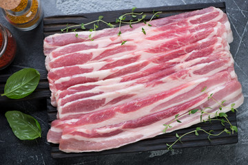 Wall Mural - Close-up of fresh uncooked bacon with fresh thyme and basil, view from above