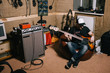 Guitarist in old garage recording studio. Messy music basement with instruments, album making process
