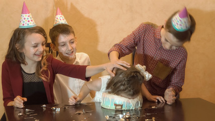 carefree children at a birthday party. friends dunked birthday girl face in the birthday cake.