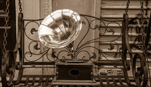 Gramophone Standing On The Vintage Swing At Flea Market In Paris (France). Old Times Background. Aged Photo. Sepia.
