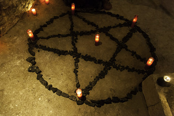 Satanic pentacle with candles in a dark ritual