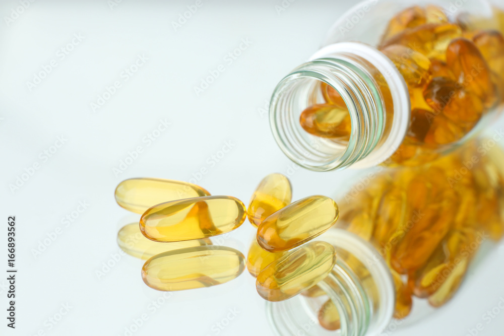 Bottle with fish oil capsules on mirror background