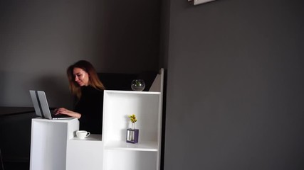 Wall Mural - Charming girl manager loves work and composes business plan or answers important messages on net and sits at table in stylish modern office on working day. Beautiful European woman with fair-haired