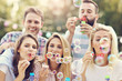 © Kalim - Happy group of friends blowing bubbles outdoors
