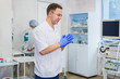 © romankosolapov - Handsome mature surgeon in blue medical wear and mask is putting on medical gloves at operating room