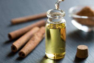 A drop of cinnamon essential oil is being dropped into a bottle