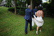 © holly - Bride and Groom Walking with Groom Holding up the Train of the Wedding Dress
