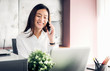 © weedezign - Asian businesswoman talking on mobile phone in front of laptop computer at office,Office lifestyle concept