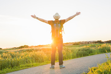 Man with arms raised, looking out over field