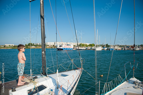 Fotografie, Obraz one healthy happy small boy wearing sunglasses aboard luxury boat in port