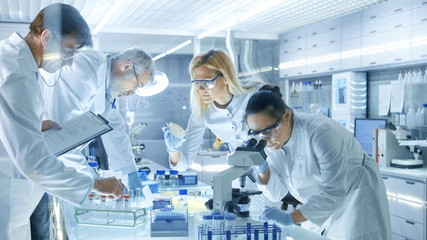Wall Mural - team of medical research scientists work on a new generation disease cure. they use microscope, test