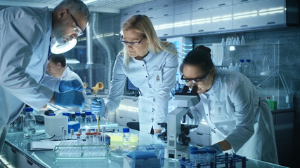 Wall Mural - Team of Medical Research Scientists Work on a New Generation Disease Cure. They use Microscope, Test Tubes, Micropipette and Writing Down Analysis Results. Laboratory Looks Busy, Bright and Modern.