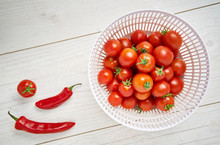 Fresh Ripe Red Tomatoes And Chillies In A Colander On A Pale Wood Work Surface, Worktop Background