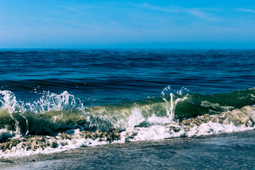 Close up of a wave crashing on the shore with droplets freeze-framed.