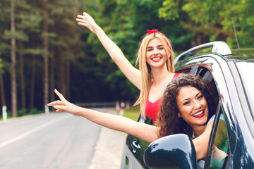 Two laughing young girlfriends traveling in a car.