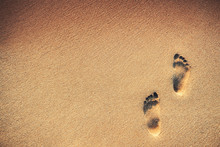 Footsteps On The Beach Over Sand Background