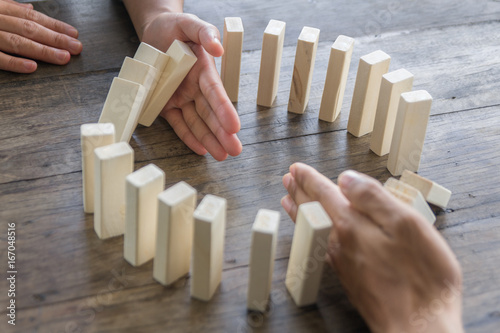 Fotografía Hand stopping domino effect of wooden blocks for concept about business and accountability